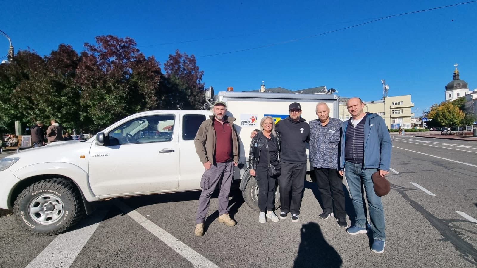 Fem vuxna människor står framför en vit bil.