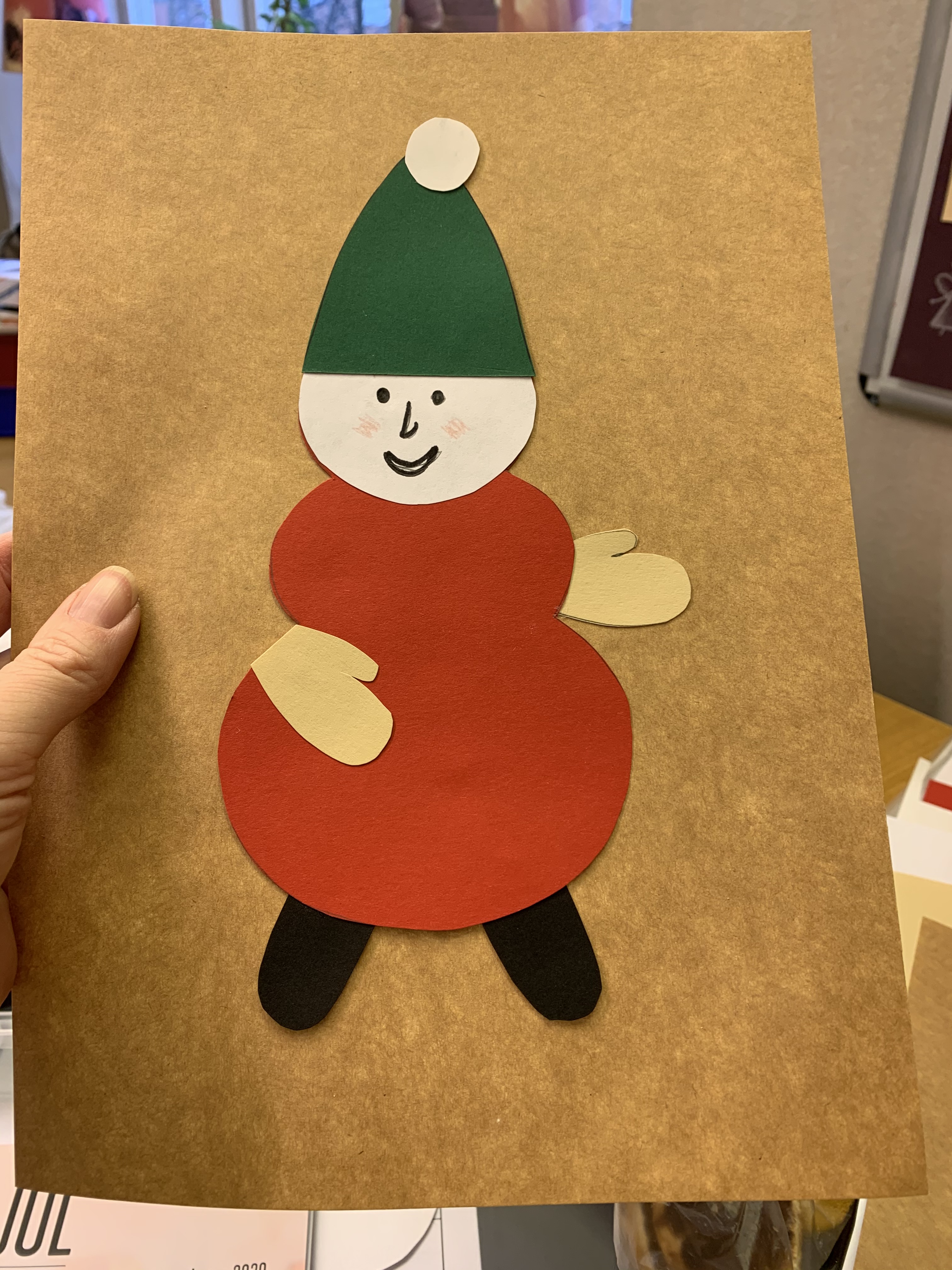 Ett kort med en tomte på som är ihoppysslad av papper i olika färger.