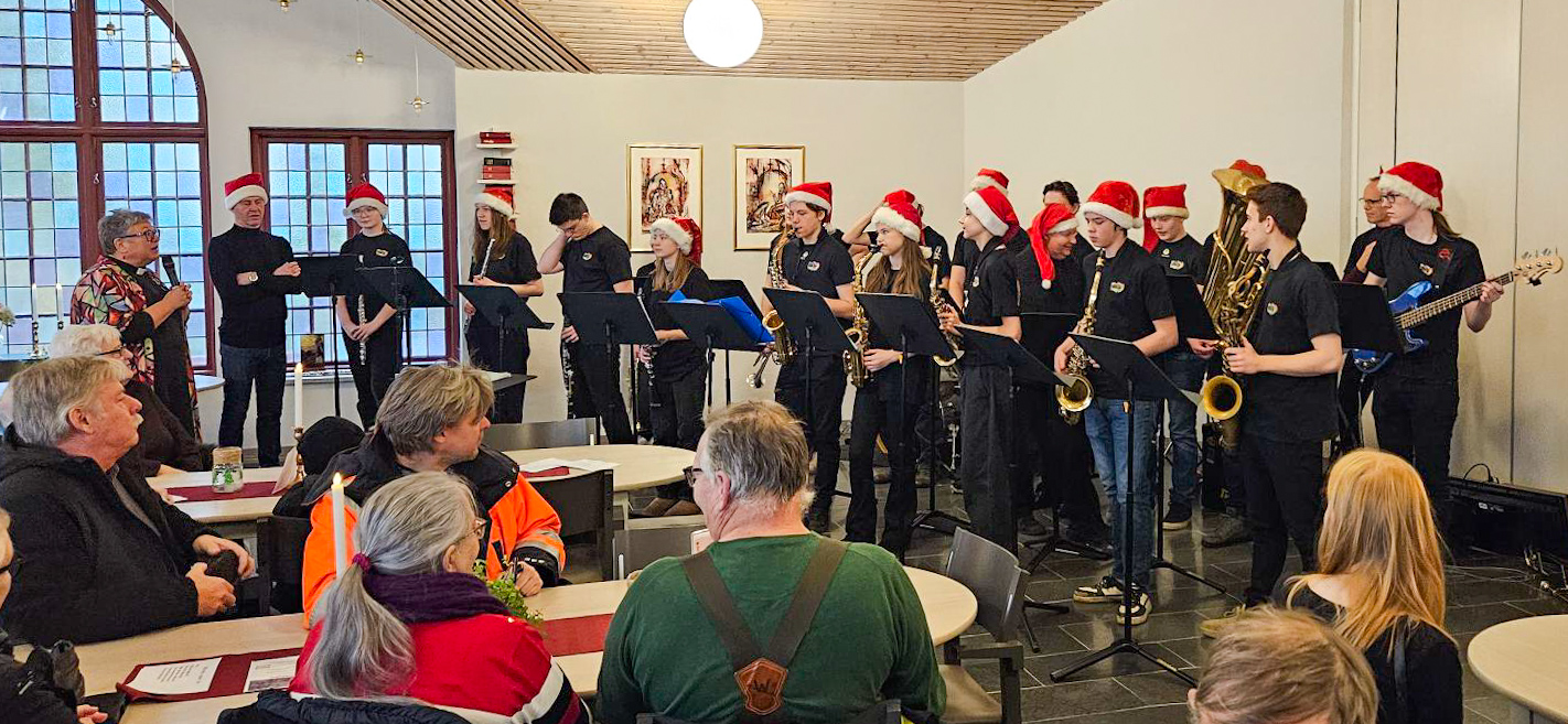 En grupp ungdomar med blåsinstrument och tomteluvor bildar en orkester.