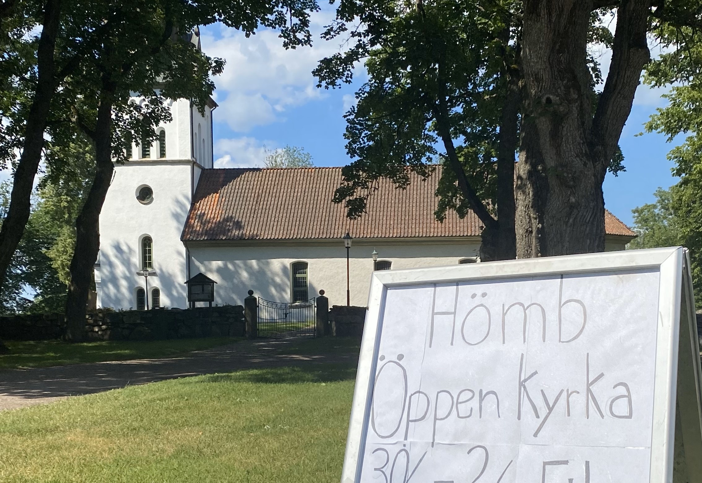 En gatupratare med information om att kyrkan är öppen, bakom skymtar en kyrka.