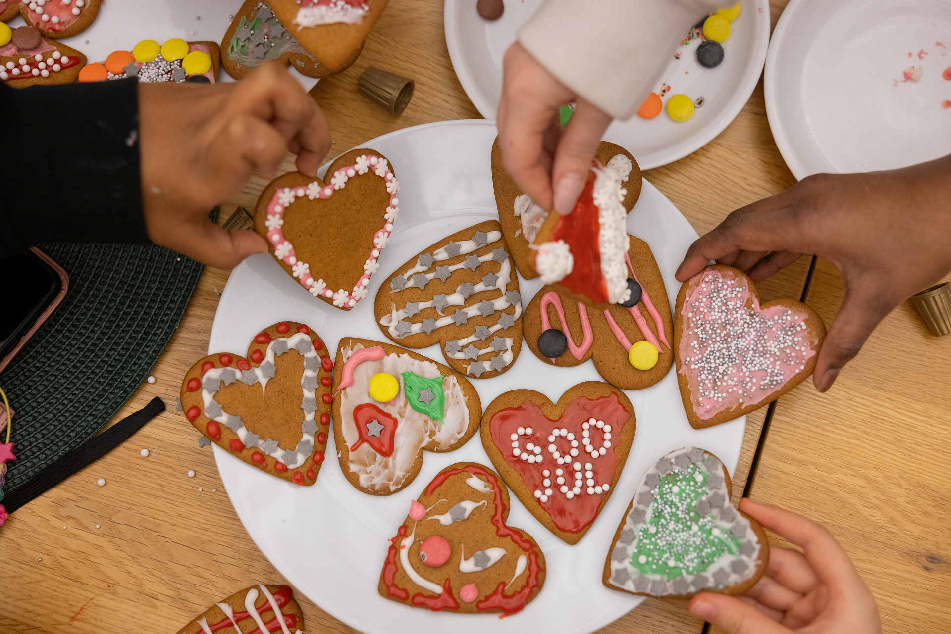 Händer som dekorerar pepparkakshjärtan.