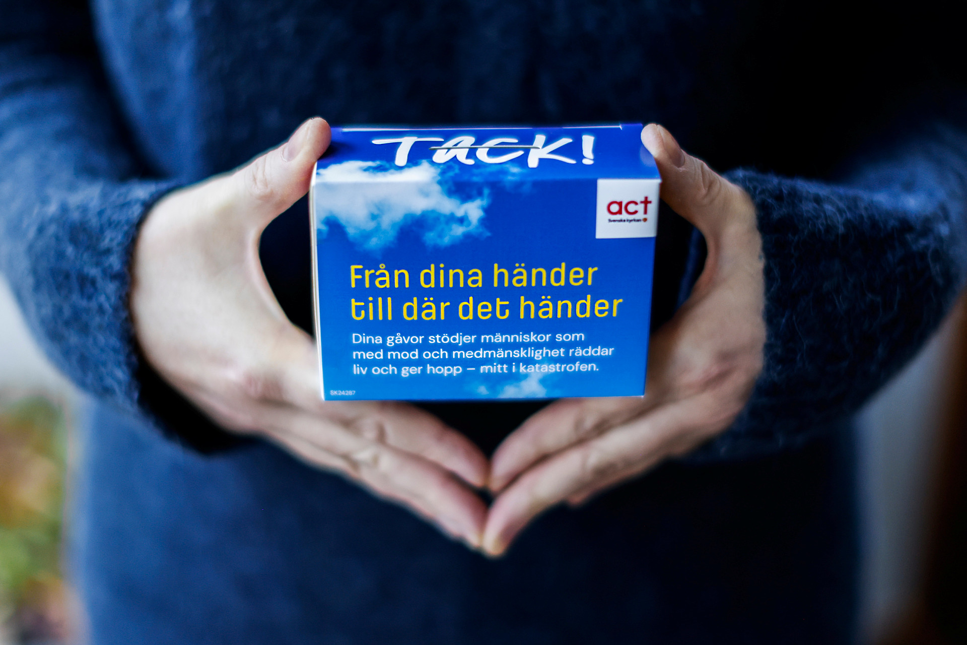 Två händer håller insamlingsbössa.