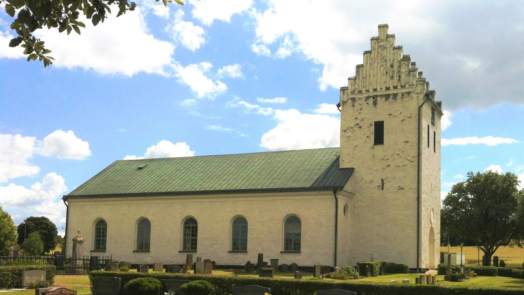 Vit kyrka mot molnig himmel.