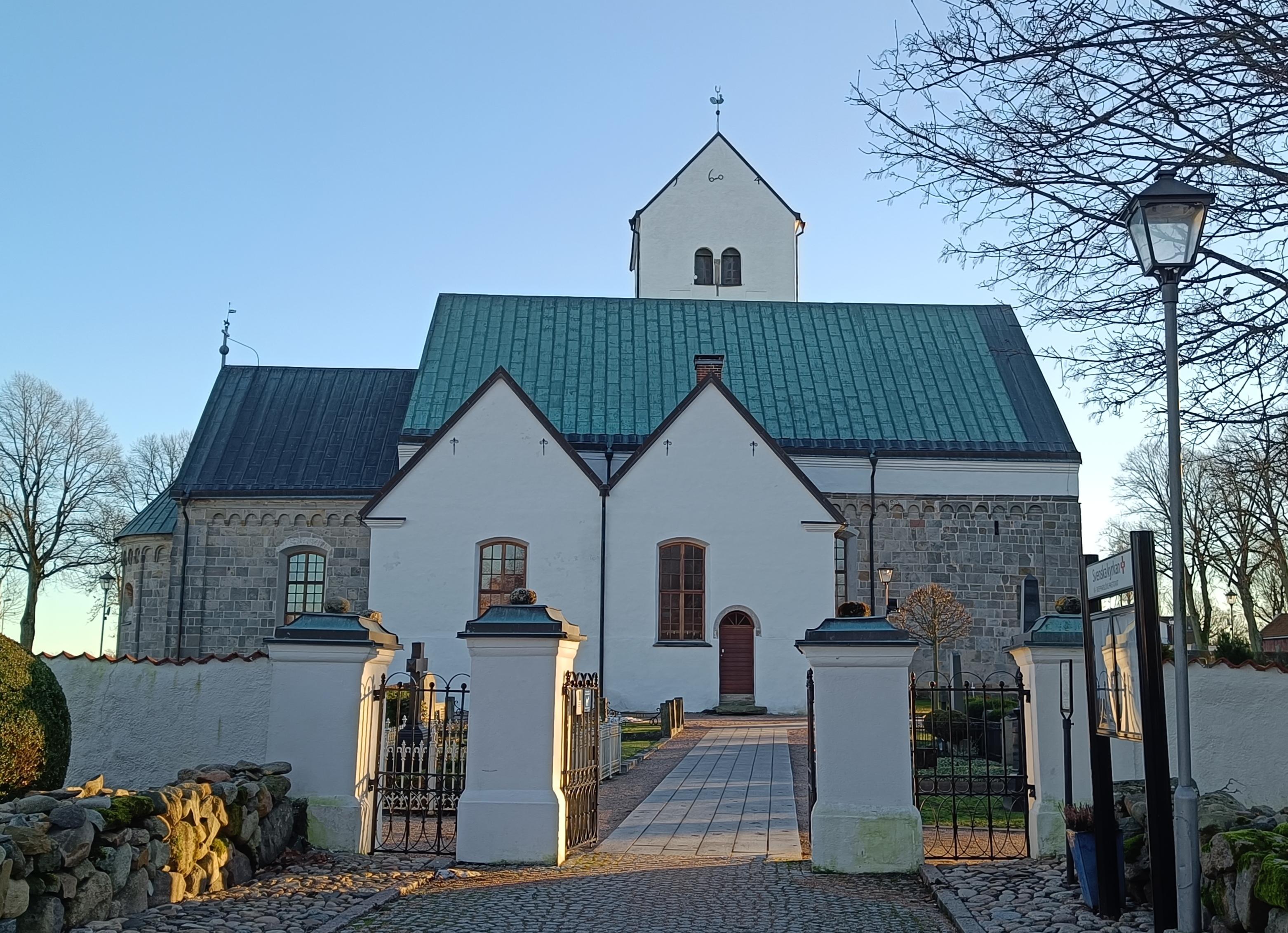 Vitkalkad kyrka mot blå himmel.