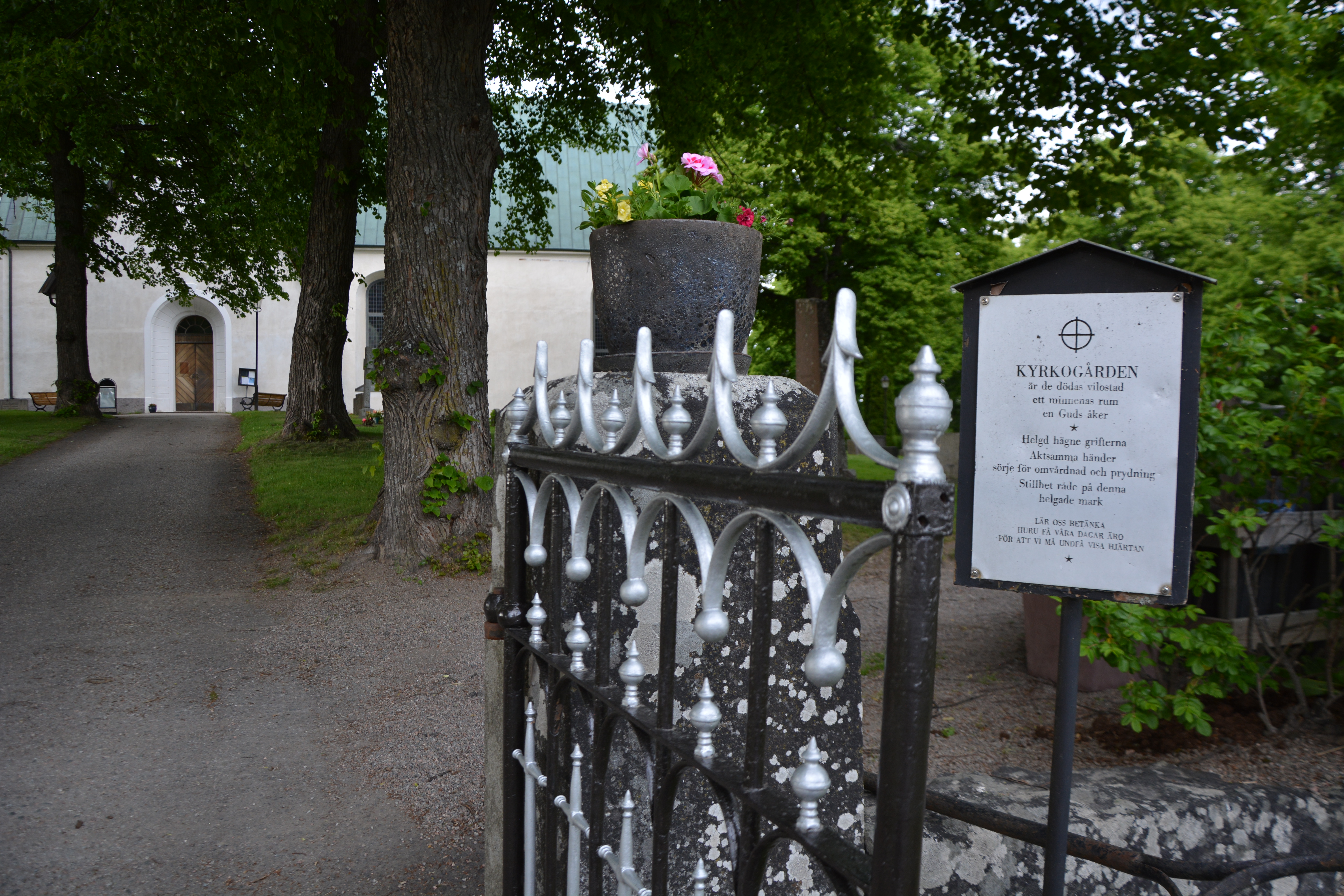Öppen smidesgrind in till kyrkogård och kyrka.