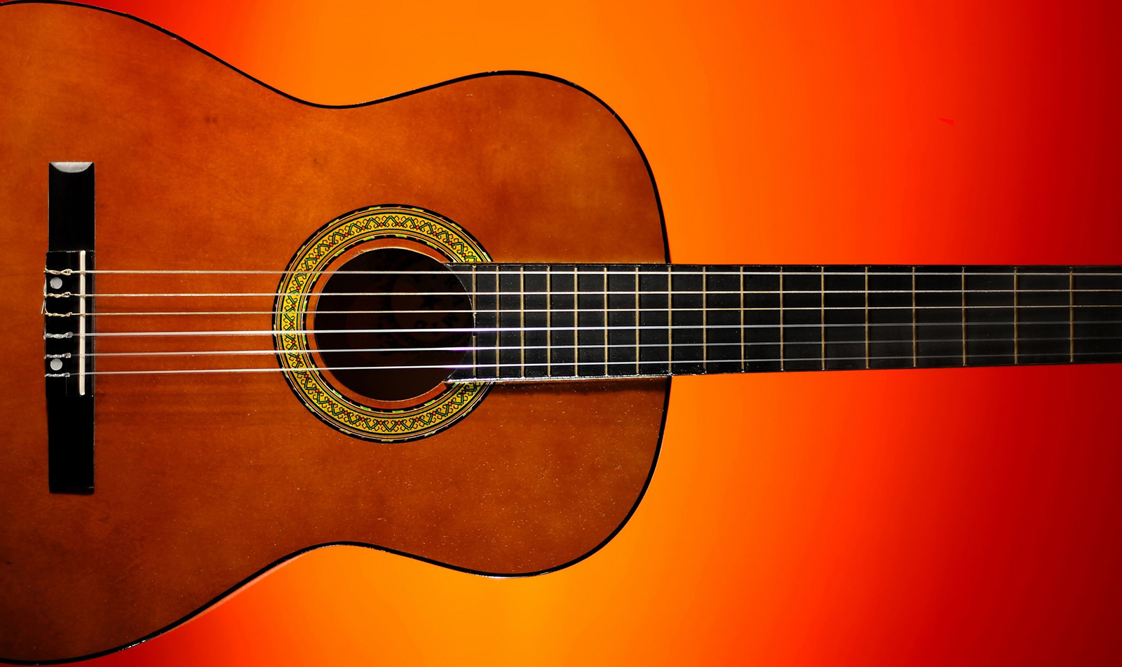 Detalj av gitarr med orange bakgrund.