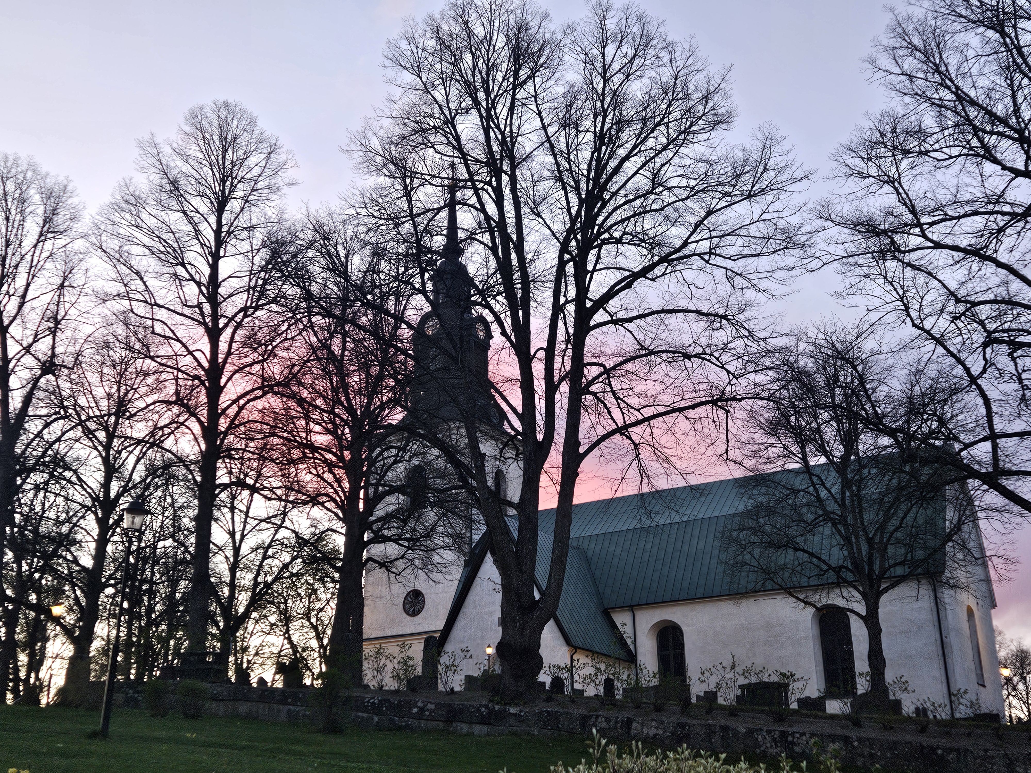Klassisk vit kyrka under rosa och lila himmel.