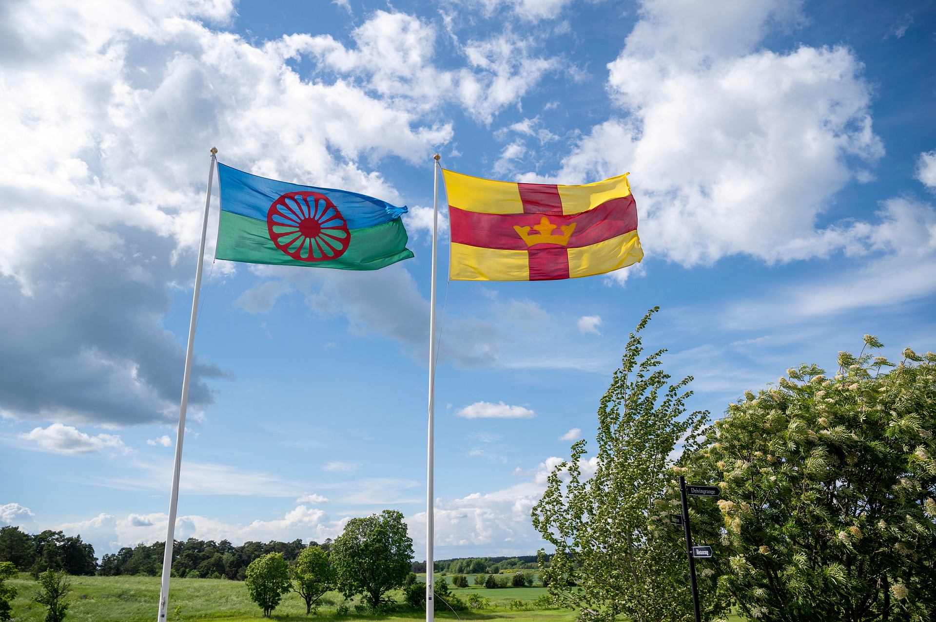 Romska och Svenska kyrkans flagga vajar bredvid varandra.