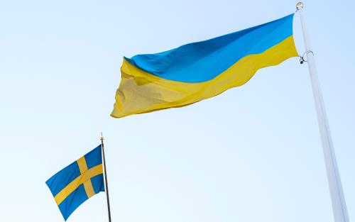 Två blågula flaggor mot ljusblå himmel, en svensk och en ukrainsk.
