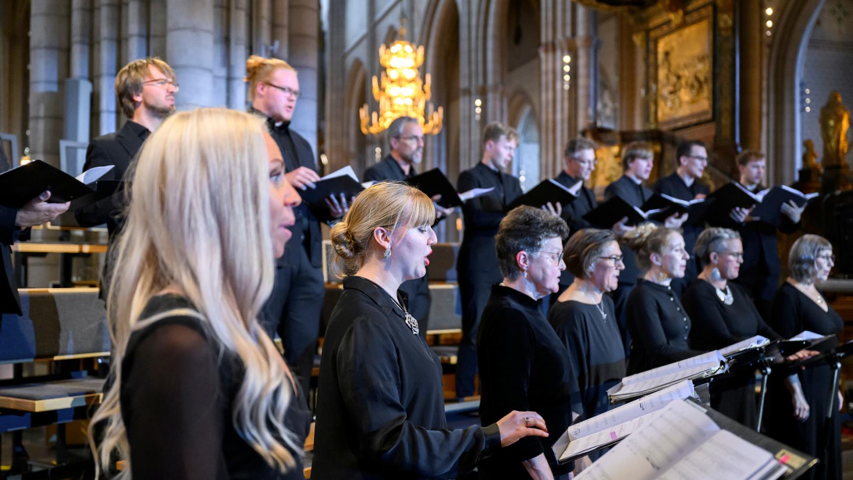 Kvinnor och män som sjunger i kör i Uppsala domkyrka. Enhetligt svartklädda framför de sång under Kyrkomusiksymposium 2022. 