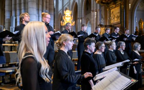 Kvinnor och män som sjunger i kör i Uppsala domkyrka. Enhetligt svartklädda framför de sång under Kyrkomusiksymposium 2022. 