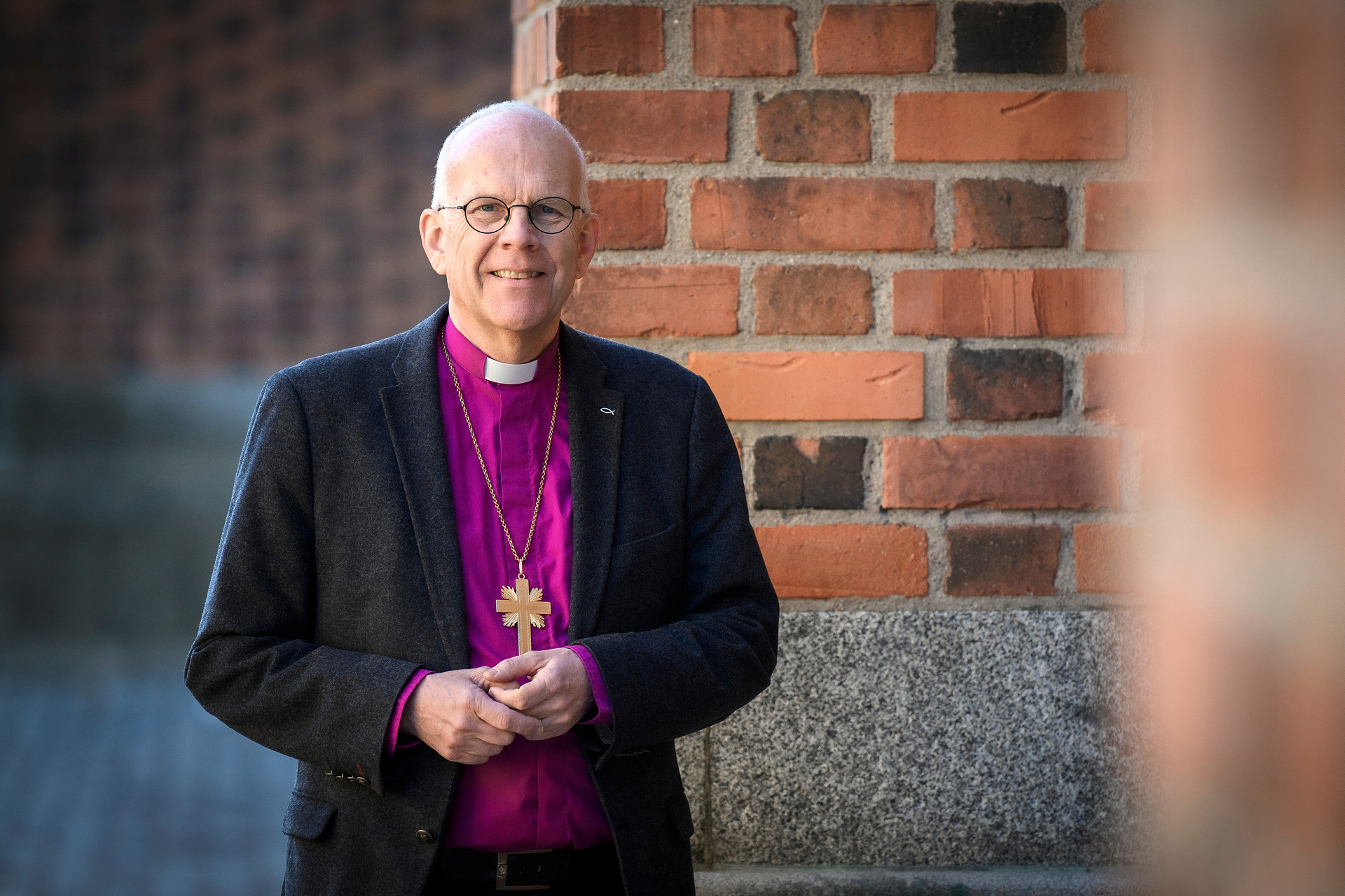 Ärkebiskop Martin Modéus i halvfigur med sin purpurfärgade biskopsskjorta och kavaj utanför Uppsala domkyrka.