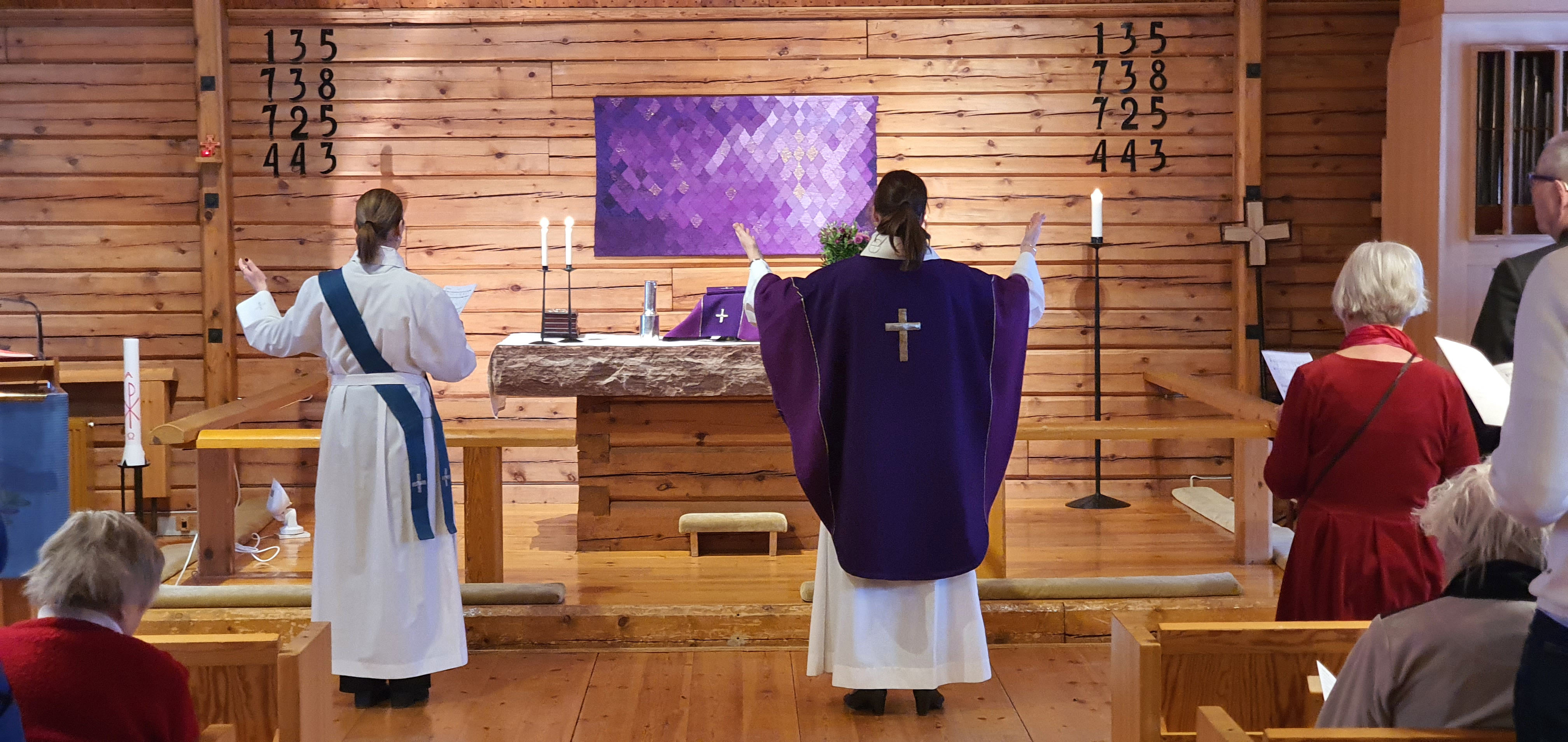 En diakon och en präst vid ett altare. De har på sig liturgiska kläder i violett.