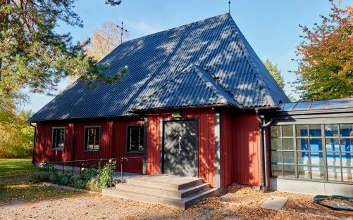 Ingången till Sunnersta kyrka. Solen som skiner på dörren silas genom tallgrenar.