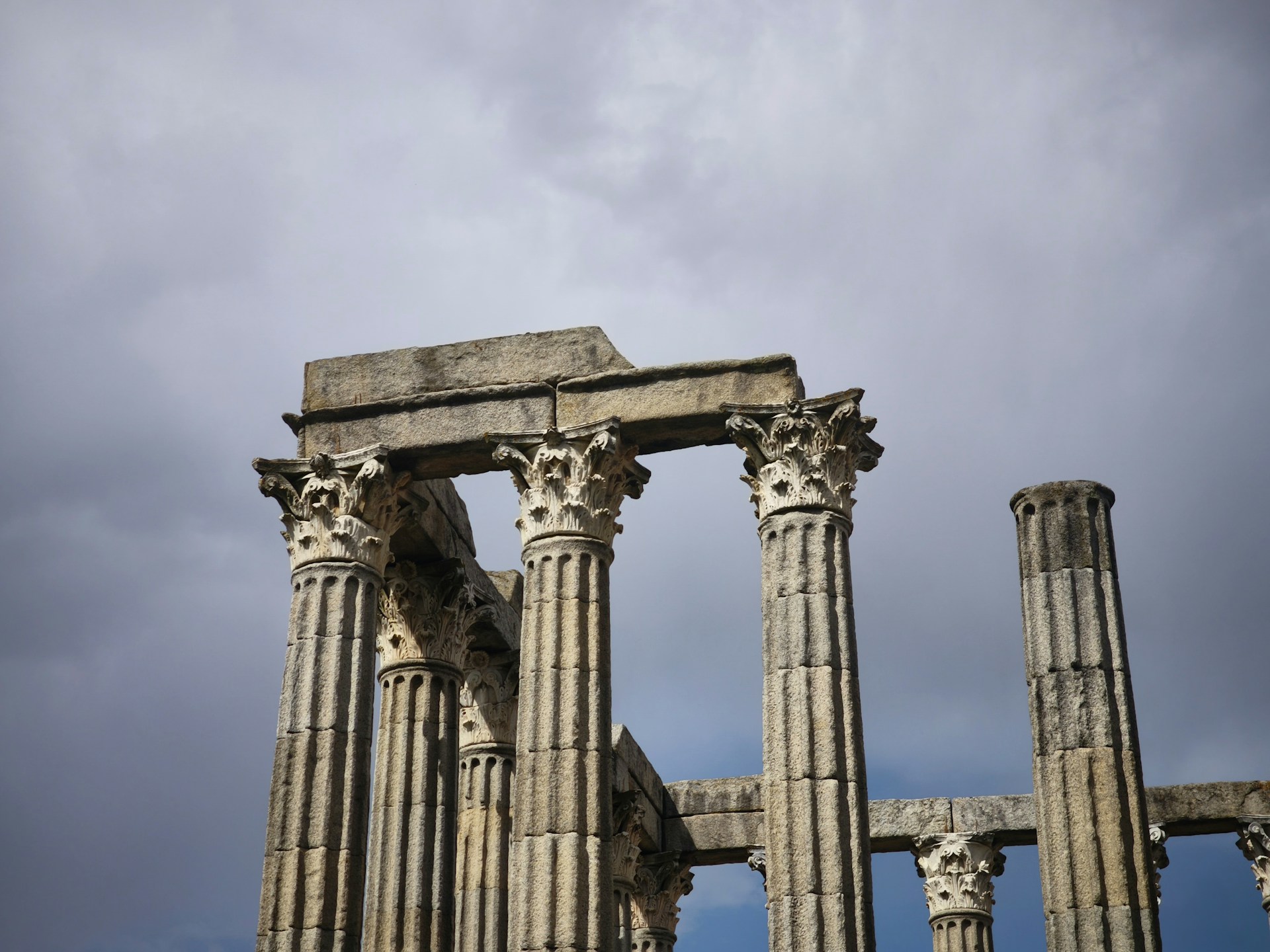 Trasiga pelare mot en himmel med mörka moln.