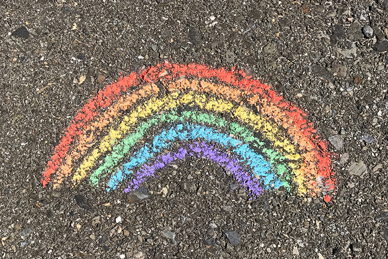 En regnbåge ritad med kritor på asfalt