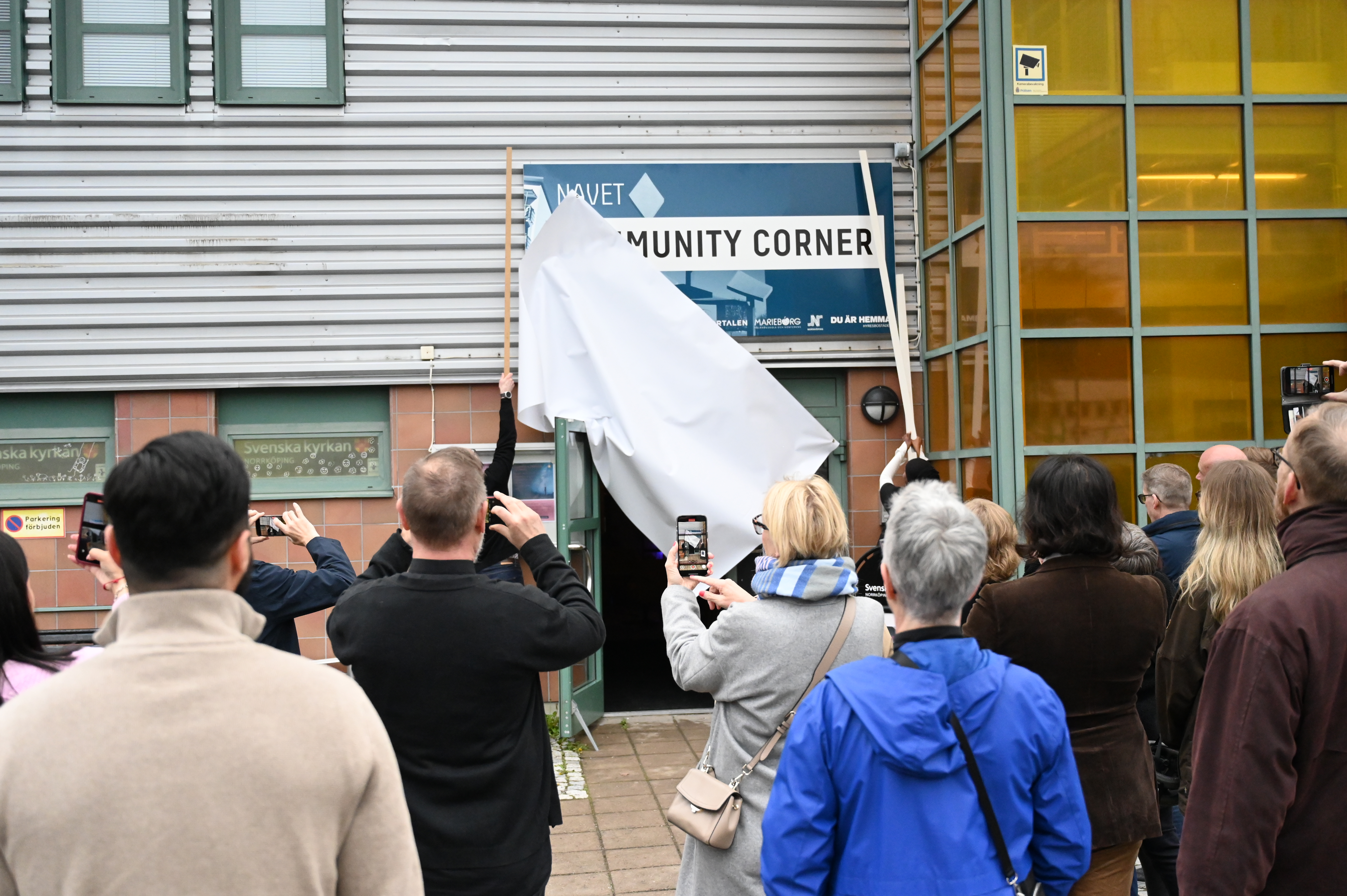 Här täcks den nya skylten för Navet Community Corner av.