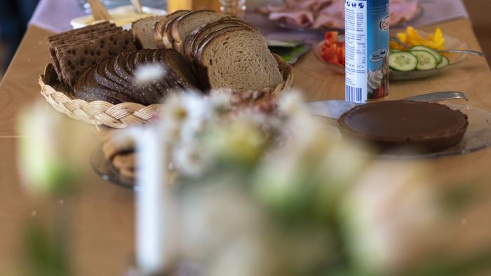 I bild syns ett uppdukat bord med bröd, smör, porslin och fika.