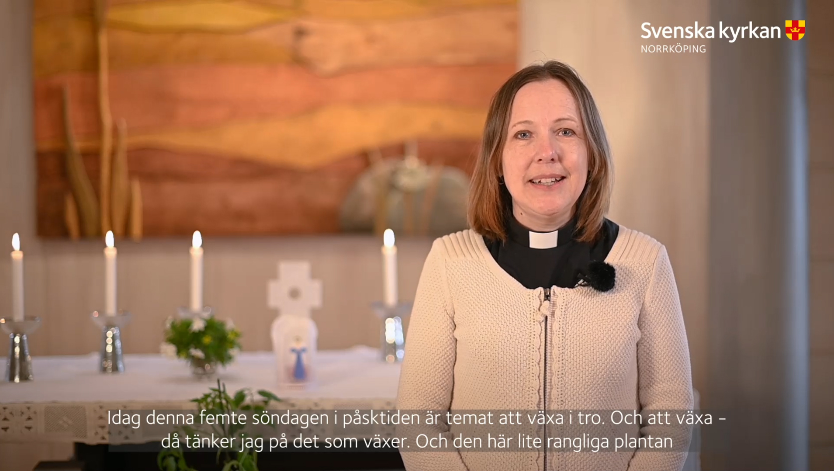 Präst Katarina Wändahl predikar framför ett altare smyckat med ljus och blommor. 