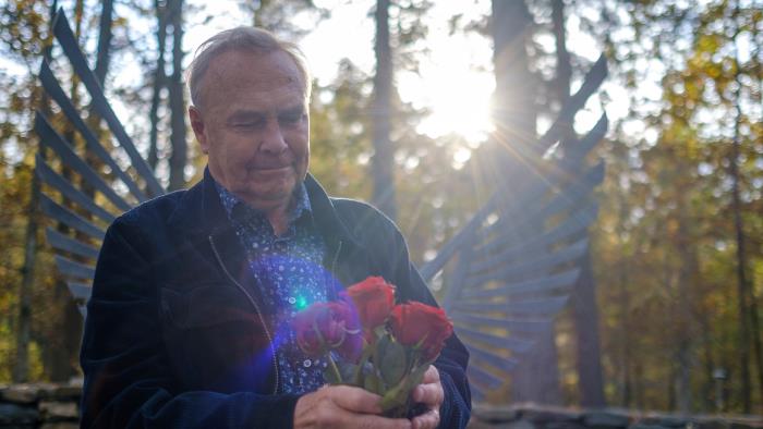 Rune Johansson med ett fång rosor i famnen vid Ekgläntans askgravplats.