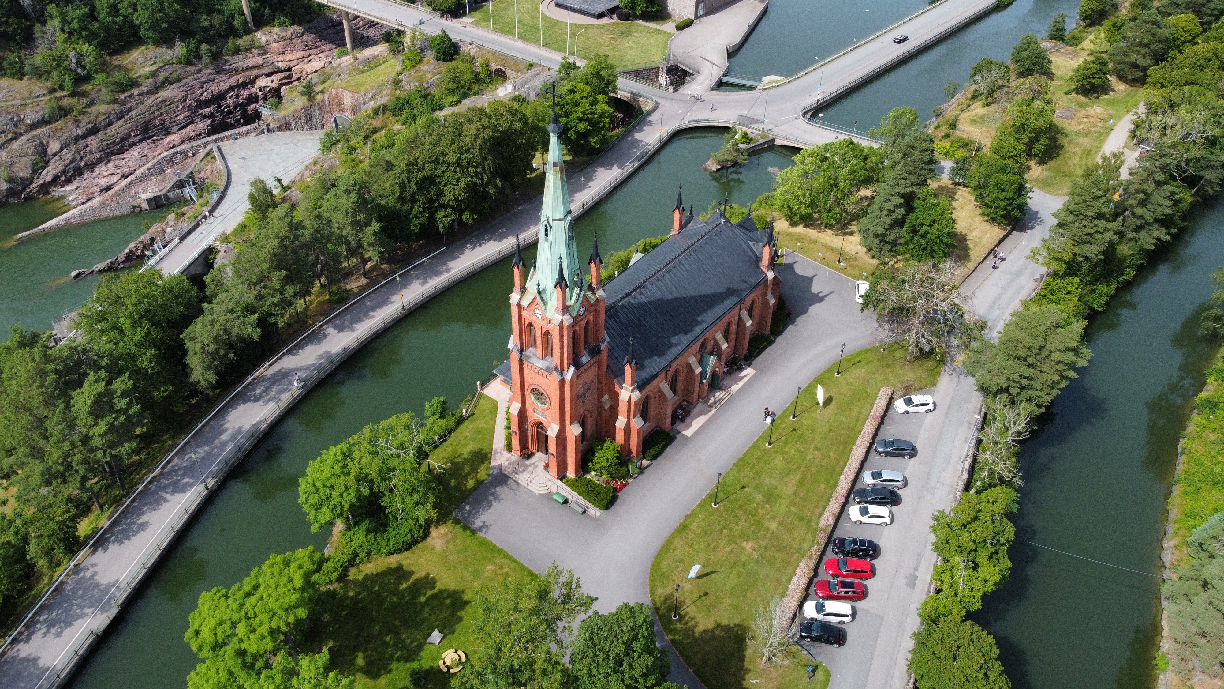 Kyrkan i sommarskrud sedd ovanifrån med omgivande Göta älv