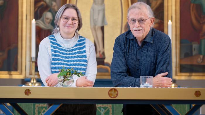 Kyrkvärdarna Amanda och Dennis framför altartavlan i Trollhättans kyrka