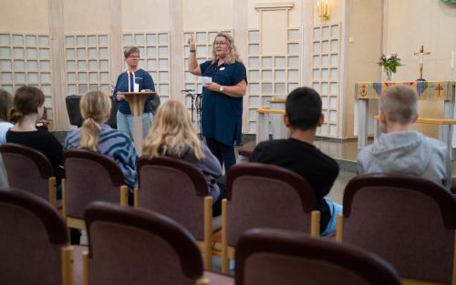Anette och Anna pratar med en skolklass i Skogshöjdens kyrka