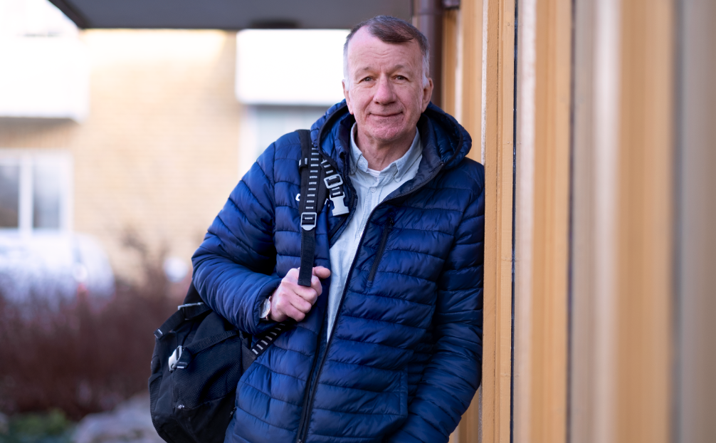 Ulf Sundberg i blå jacka lutad mot husvägg