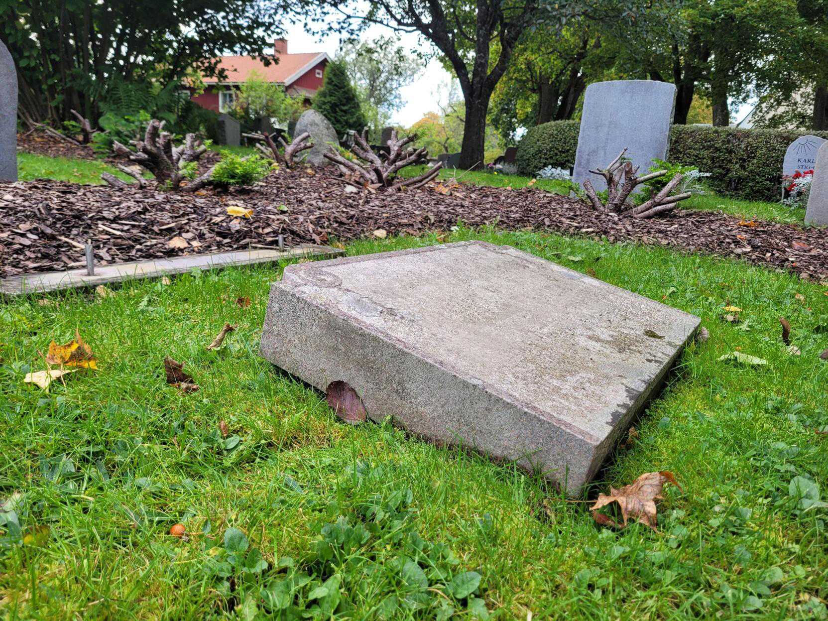 En gravsten ligger med texten uppåt i gräset