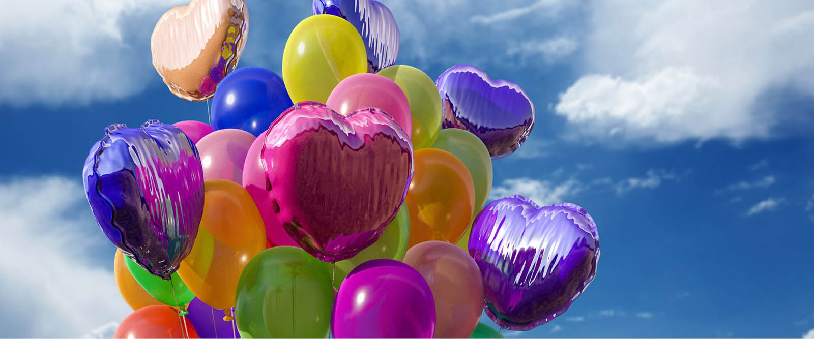 I backgrunden ser man en blå himmel med lätta vita sommarmoln. Framför ser man ett knippe färgglada ballonger i olika former .