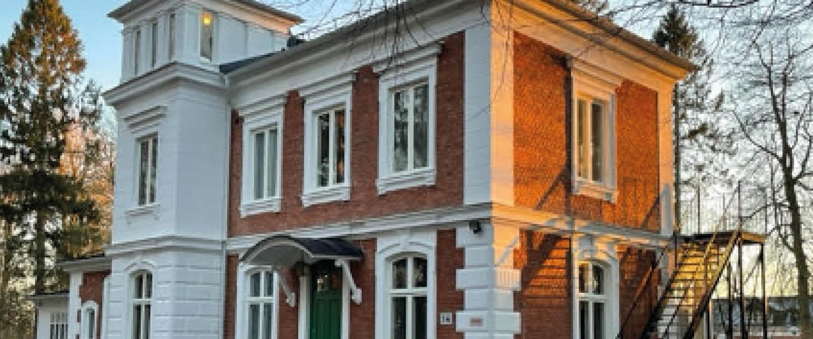 Bild på ett gammalt hus i tegelrött och vitt.