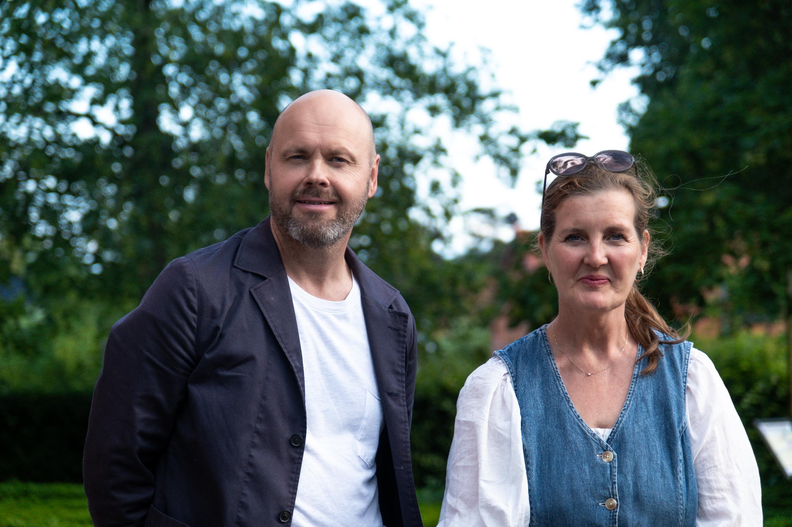 En man och en kvinna står utomhus. I bakgrunden syns grön växtlighet.