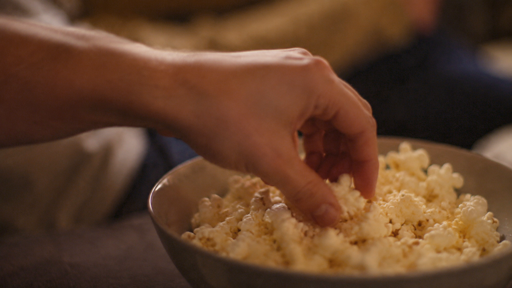 En hand sträcker sig efter popcorn.