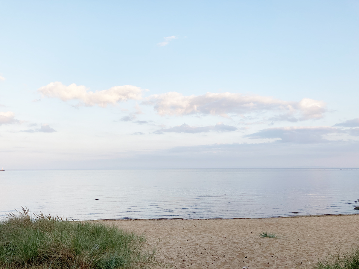 Strand och ett spegelblankt blått hav