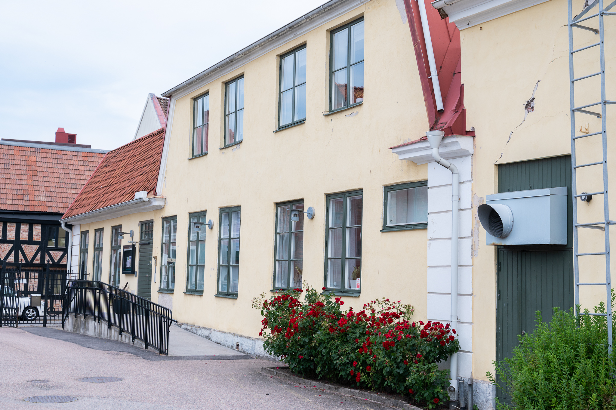 En ljusgul putsad byggnad med gröna fönster.
