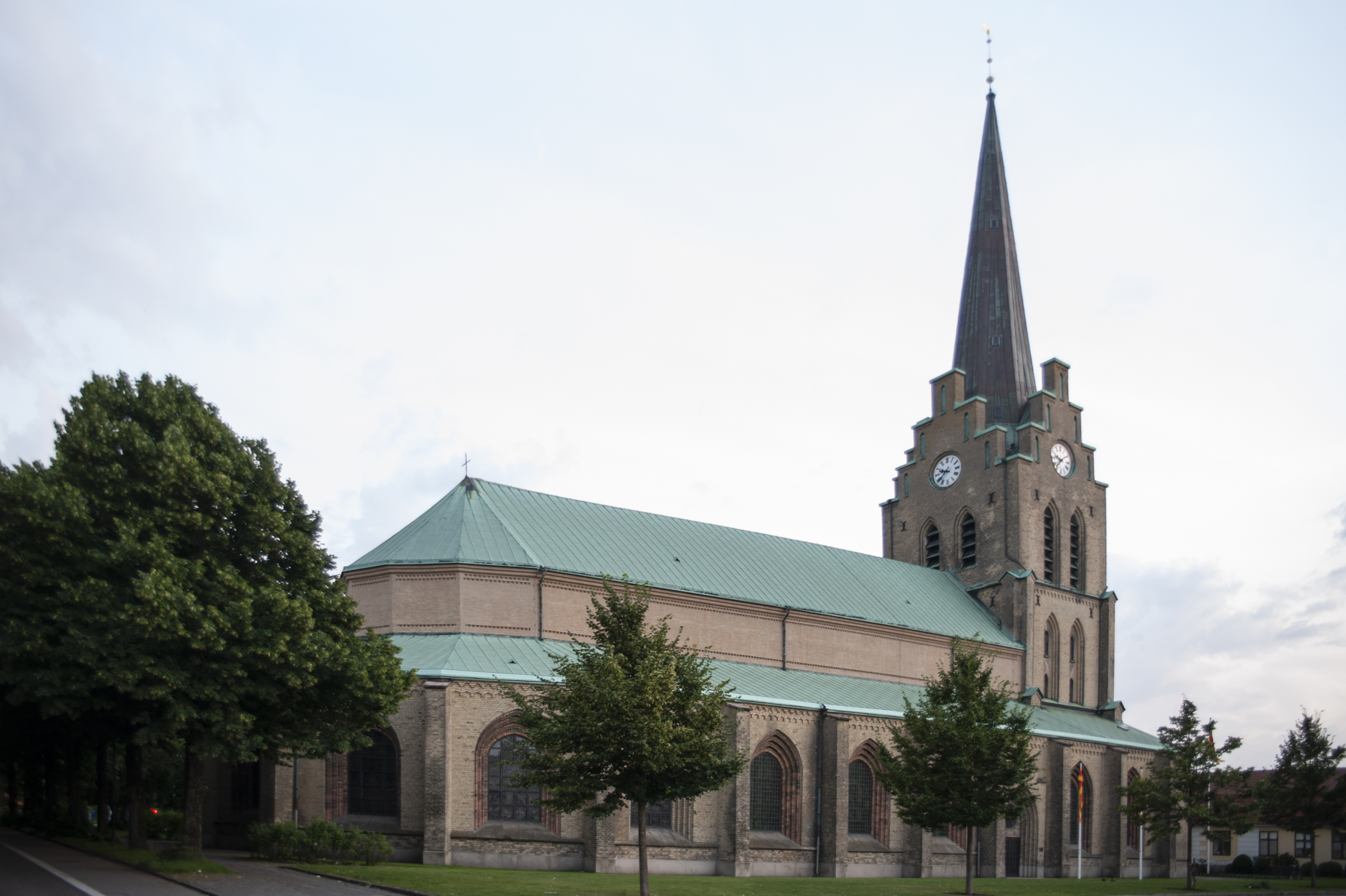 En stor gul tegelkyrka med grönt koppartak.