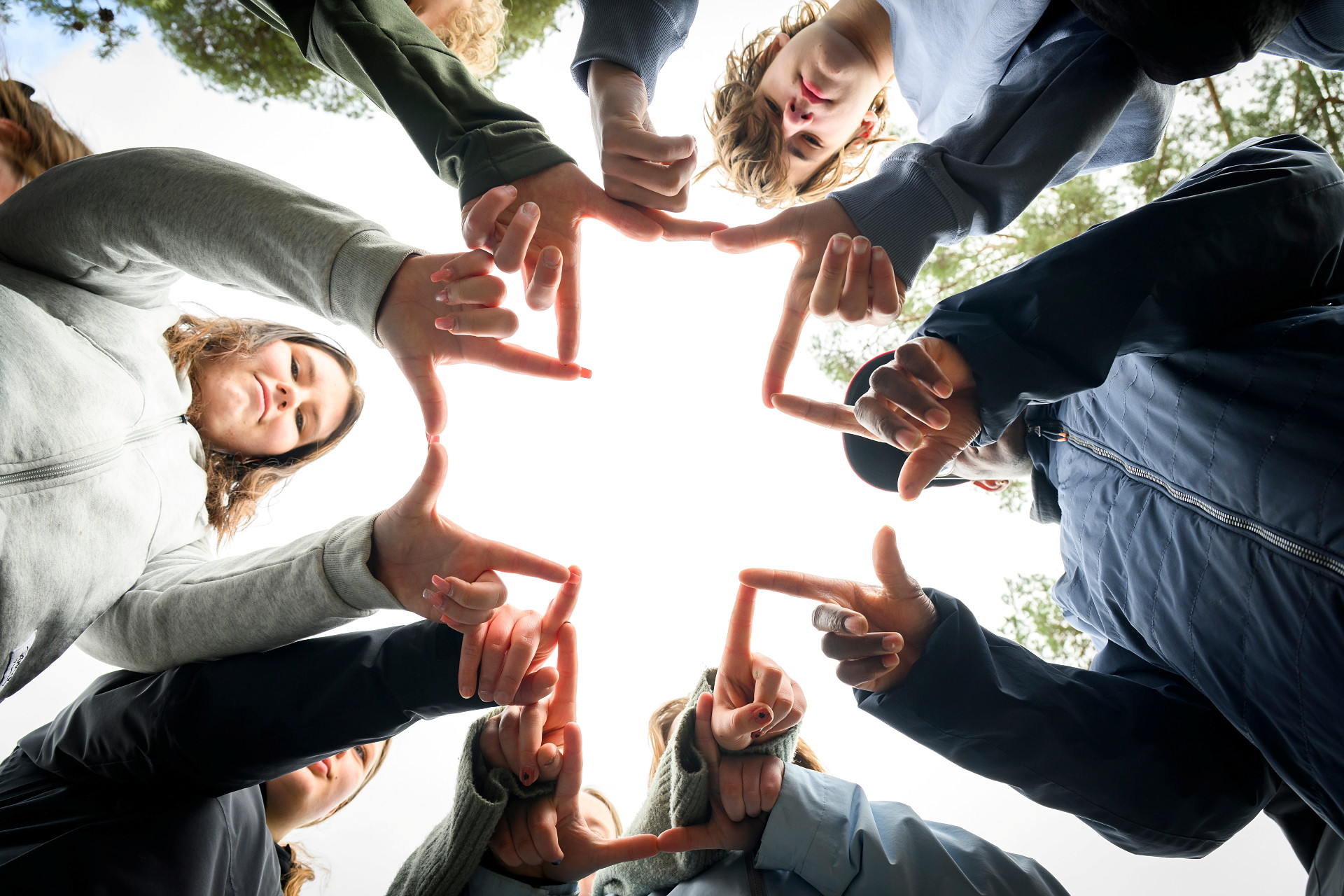 Ungdomar står och formar ett kors med sina händer och fingrar. Teckenspråkigt konfirmationsläger.