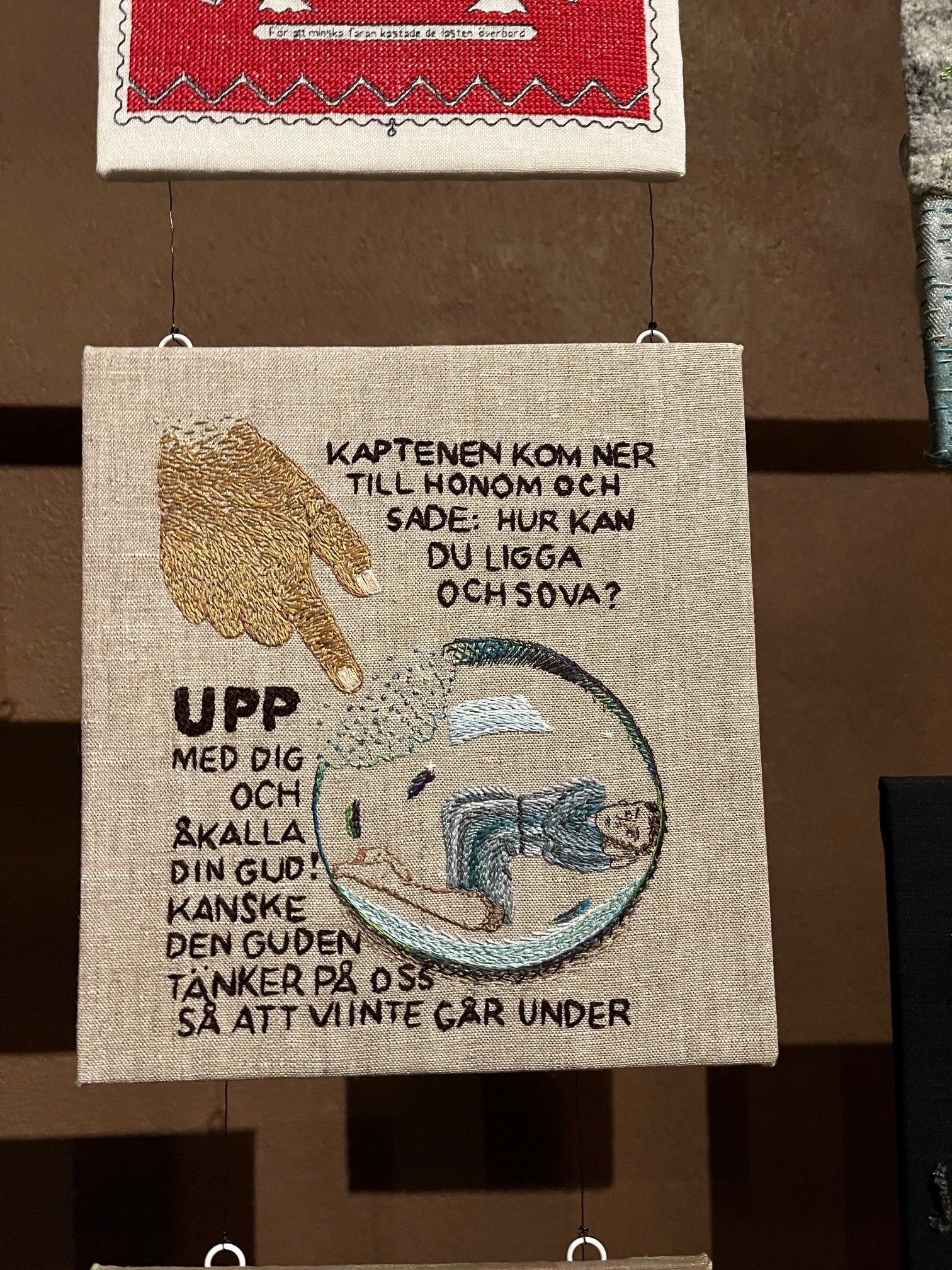 Broderad tavla med bibelord från Jona bok.