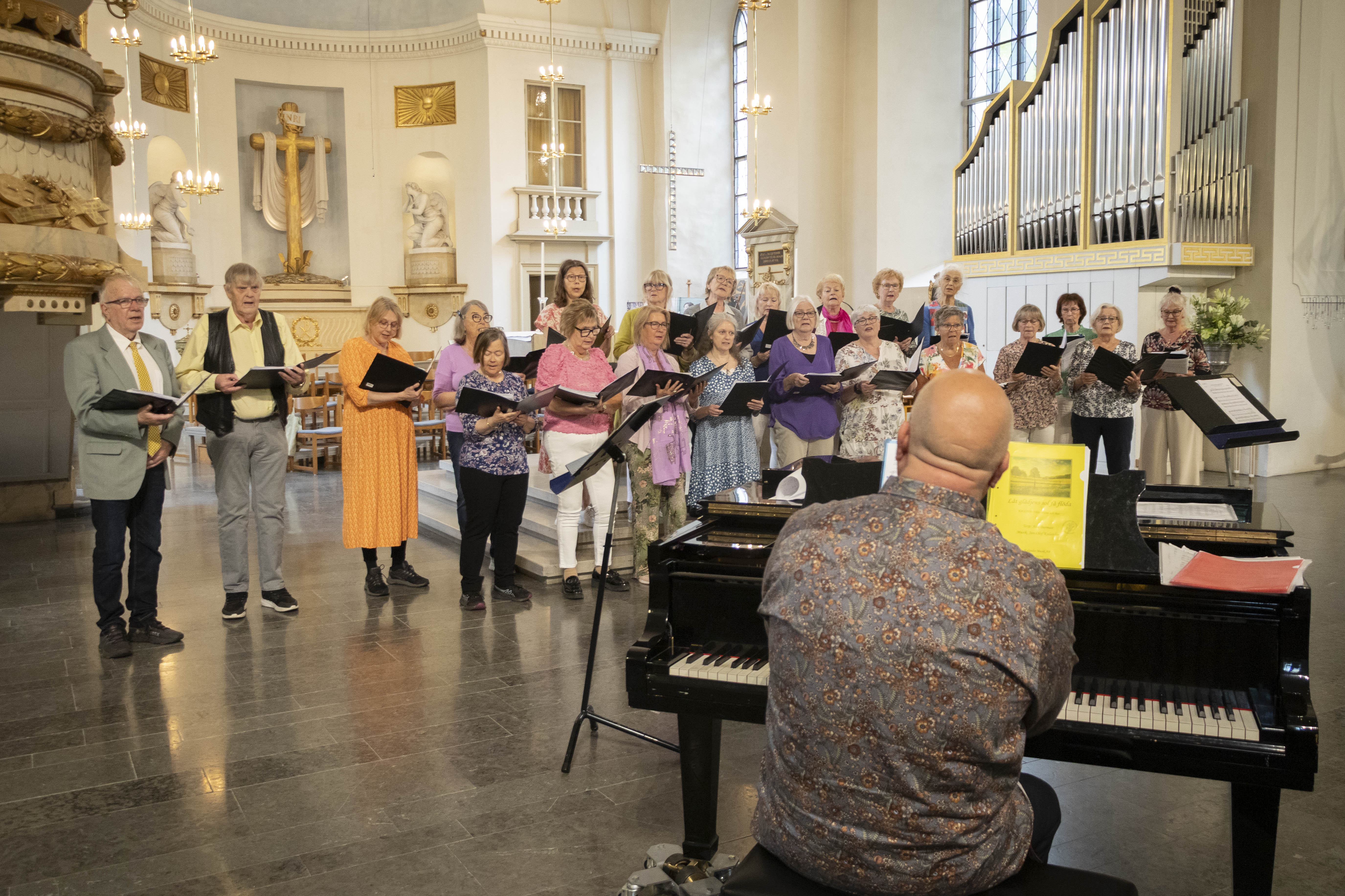 Ett trettiotal sångare sjunger med pianist i Karlstads domkyrka.