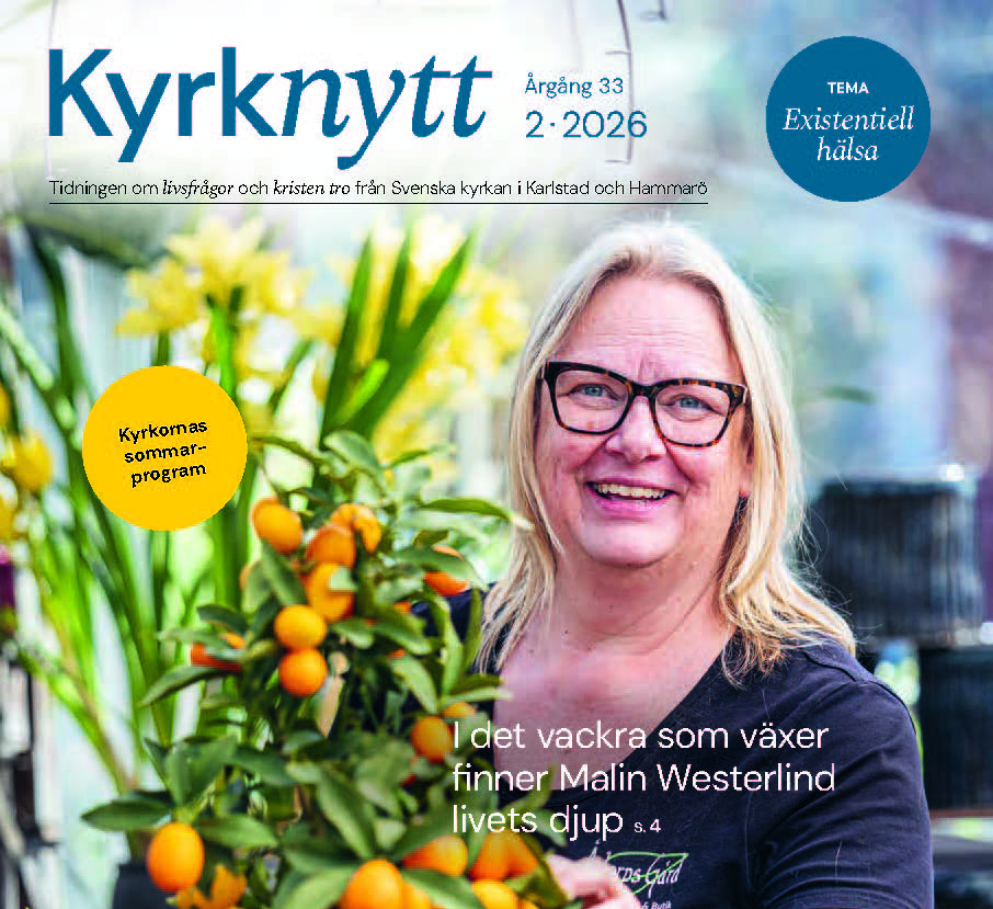 Kvinnan står i växthuset med blommor i händerna.