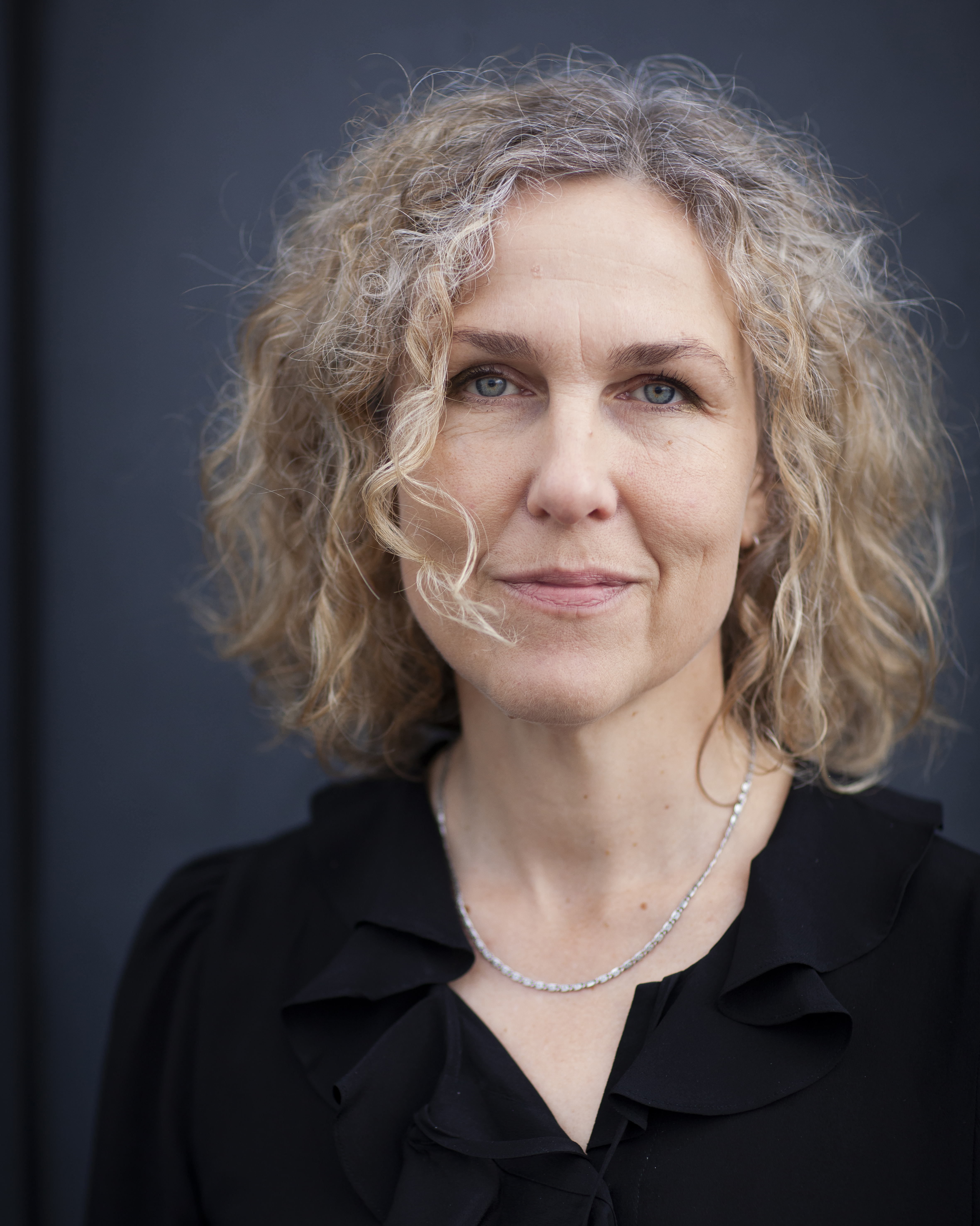Porträttbild på Marit Kapla mot mörk bakgrund