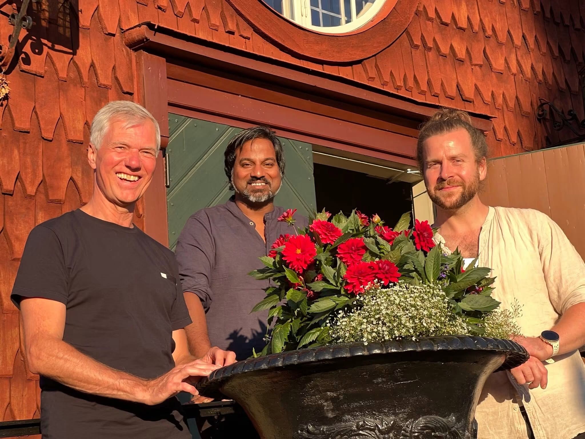 Pär Kunze, Johnny Larsson och Per-Thomas Eriksson framför en röd kyrka i sommartid