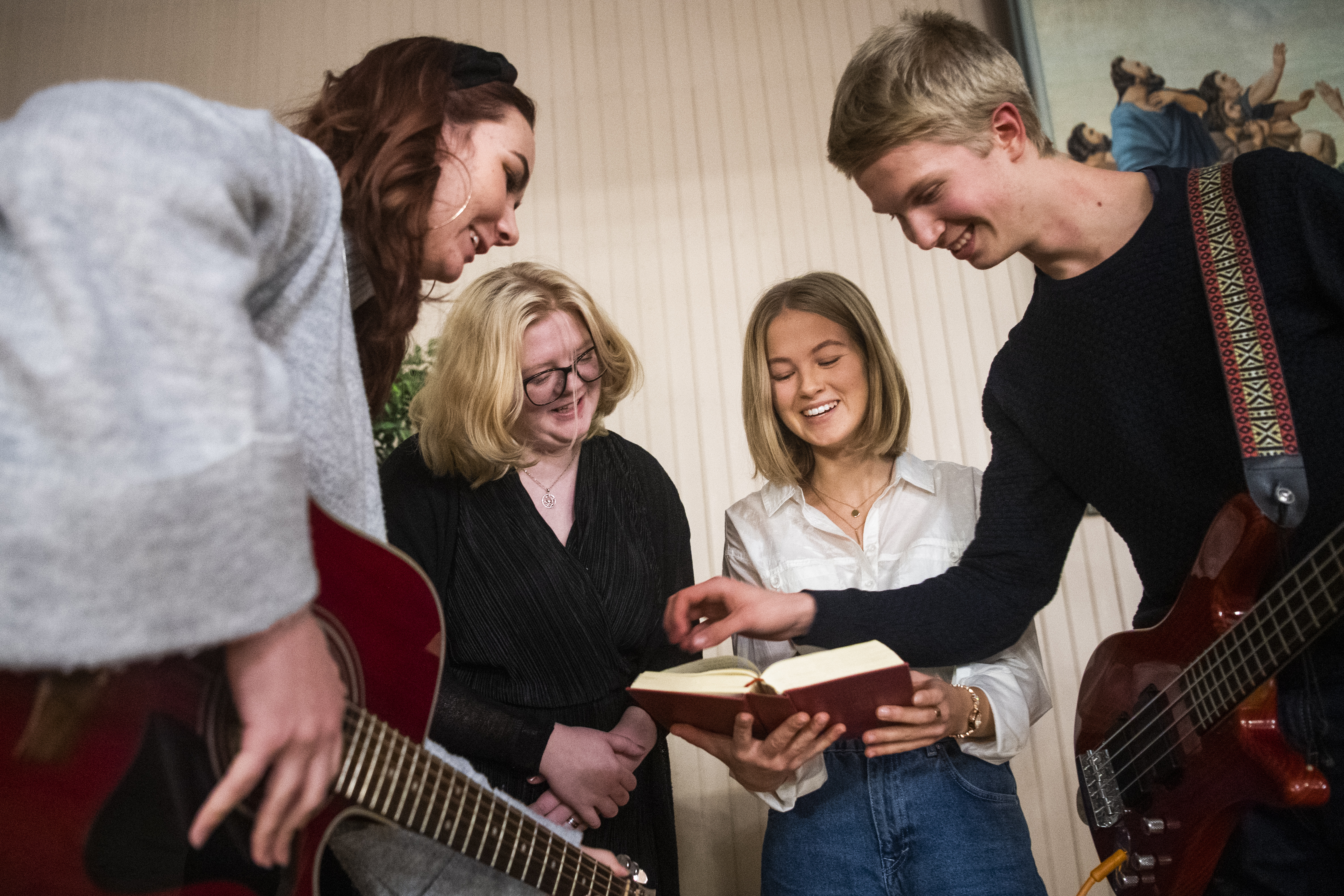 Fyra glada ungdomar tittar ner i en psalmbok. 