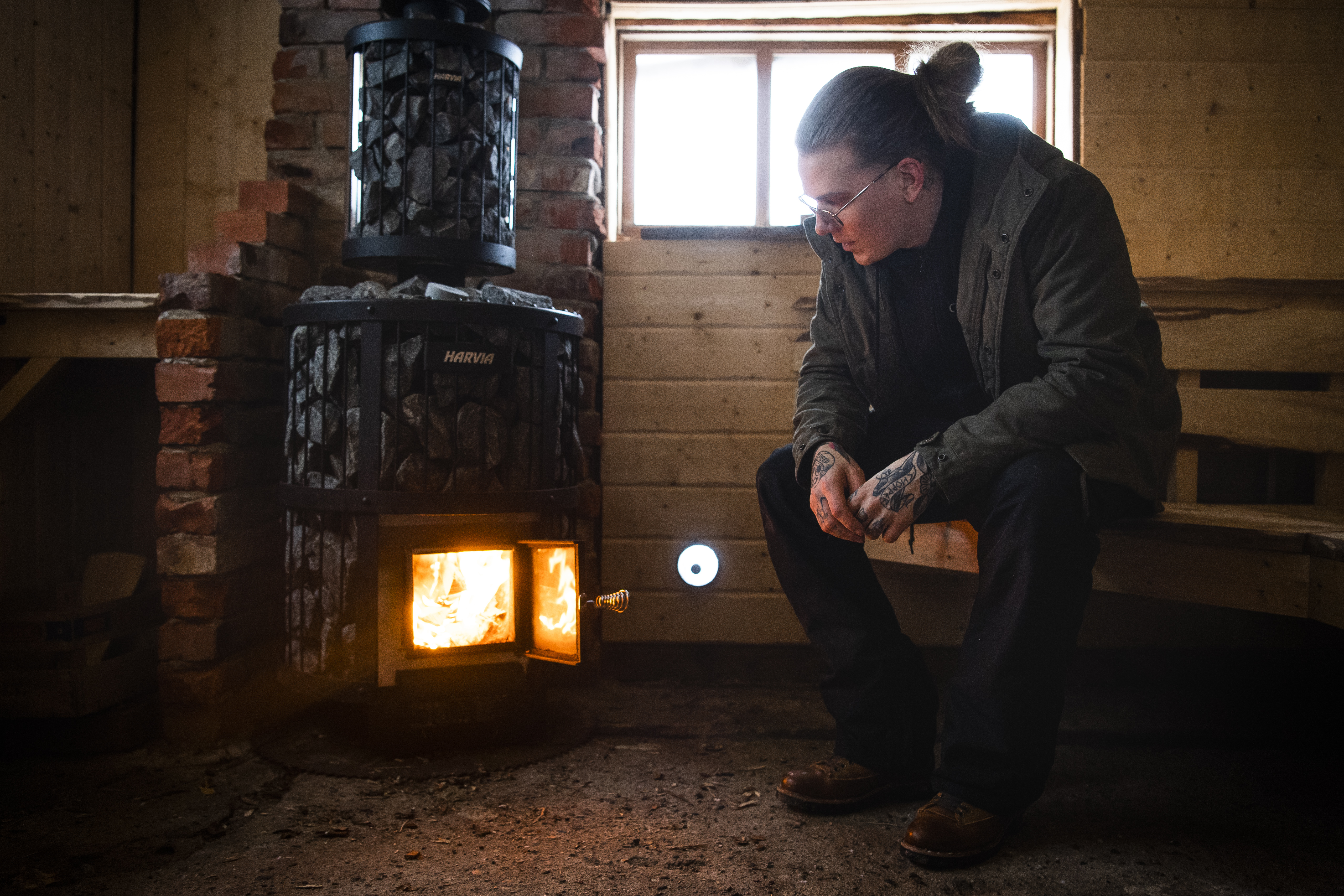 En ung man framför en bastukamin.
