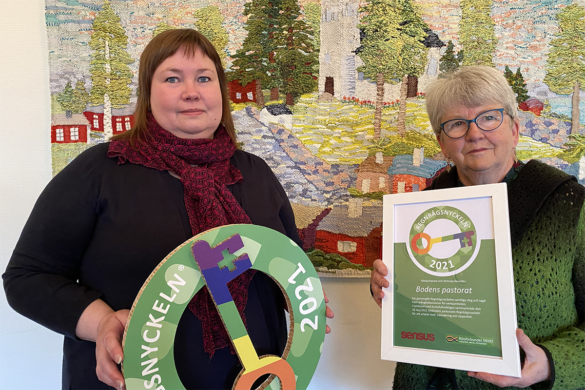 Kyrkofullmäktiges vice ordförande Erika Sjöö och ordförande Birgitta Mörk tar emot Regnbågsnyckelmärkningen för Svenska kyrkan Boden.