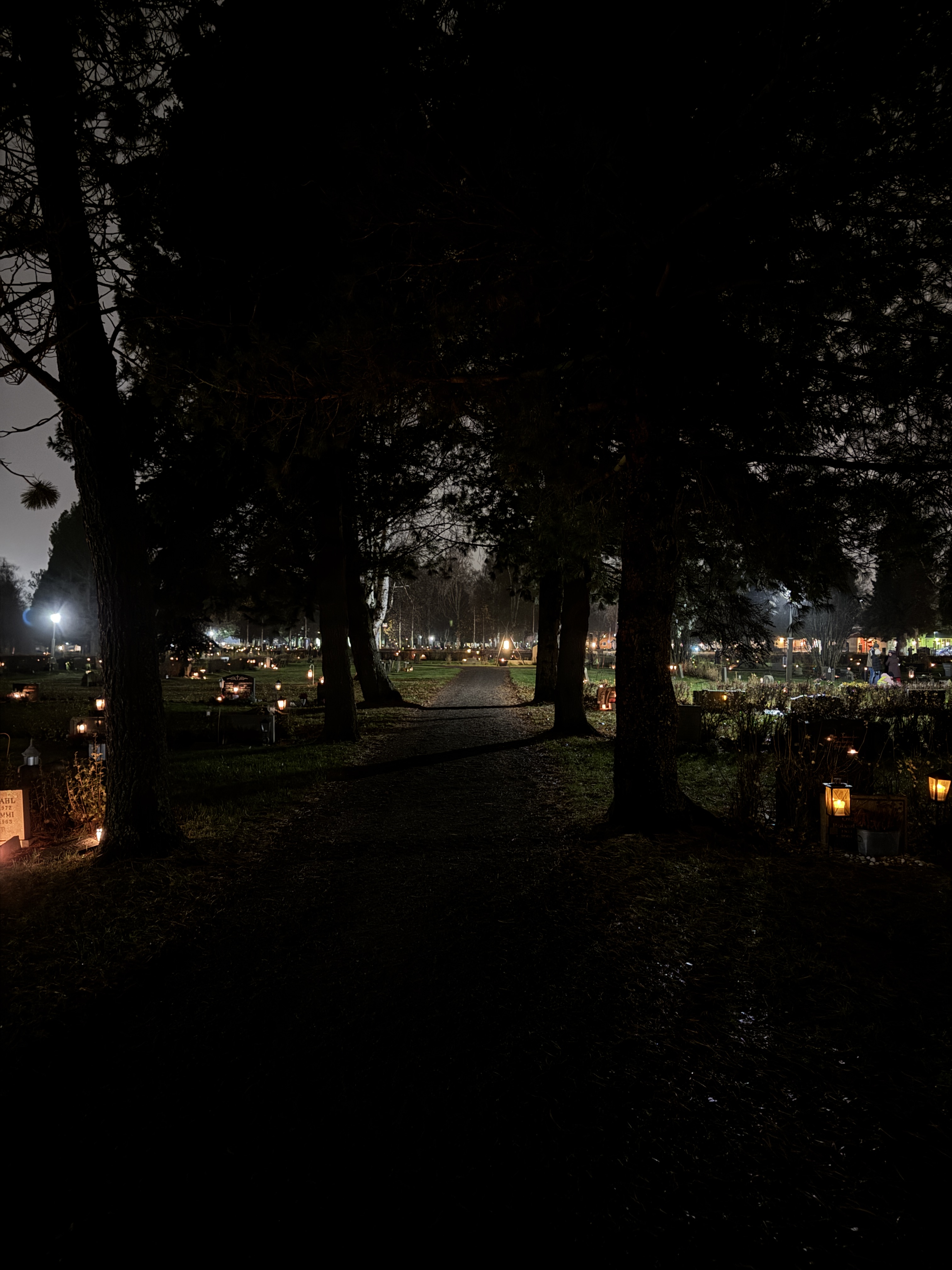 Lundagårds kyrkogård. En mörk bild där man ser alla gravlyktor lysa.