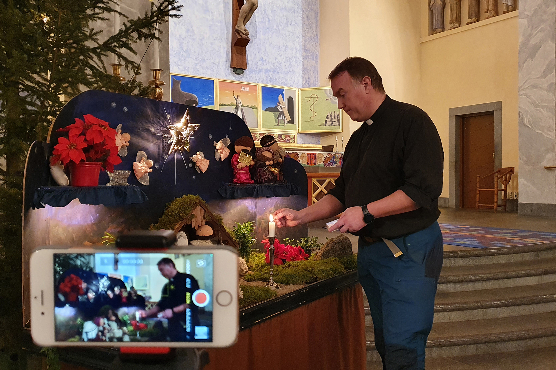 Kyrkoherde Hans Johansson tänder ljus vid julkrubban i Överluleå kyrka.