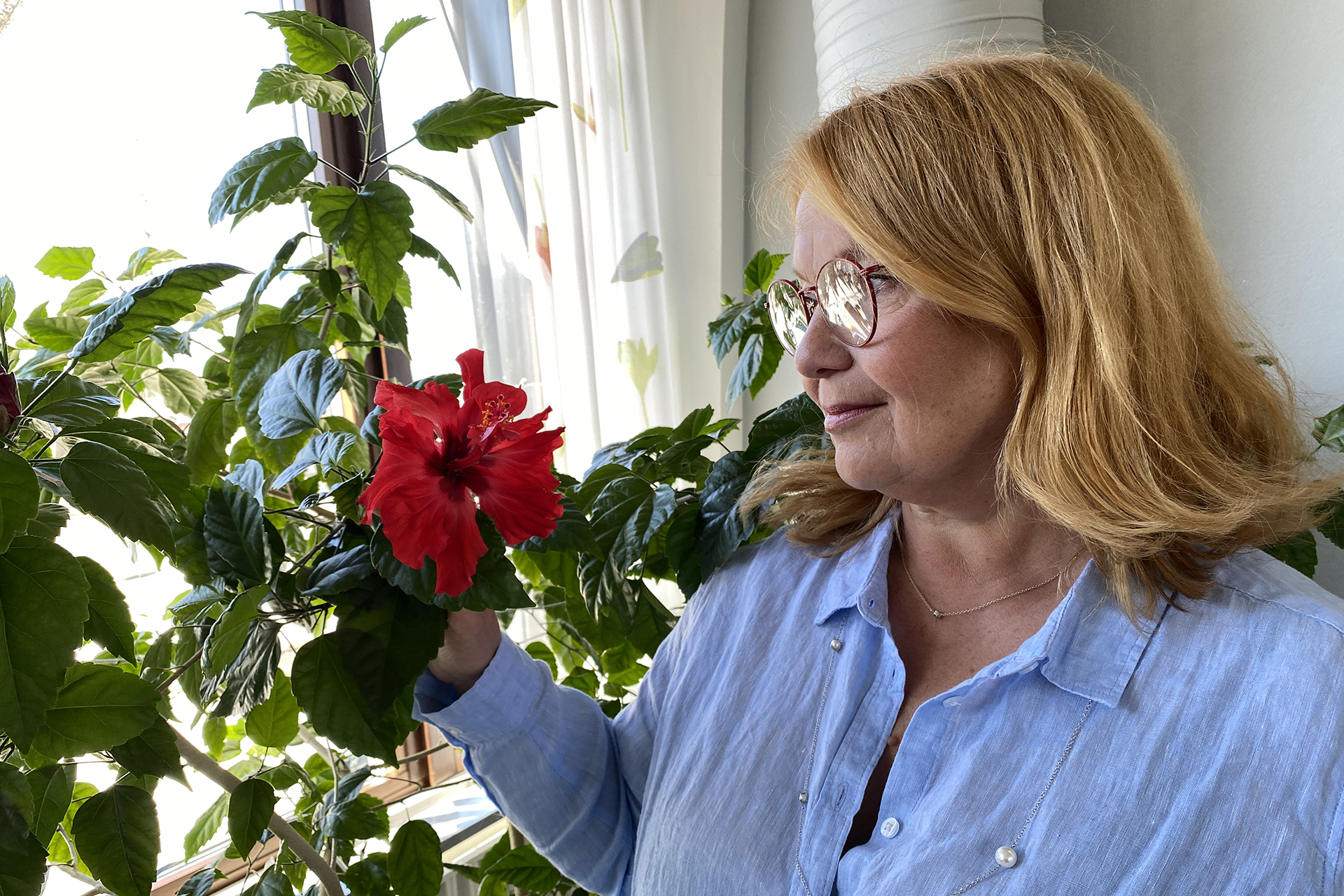 Mariana Uvemo beundrar en vacker röd blomma. 