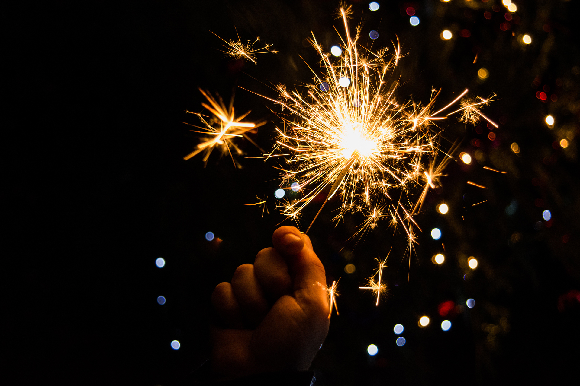 En hand håller upp ett sprakande tomtebloss.