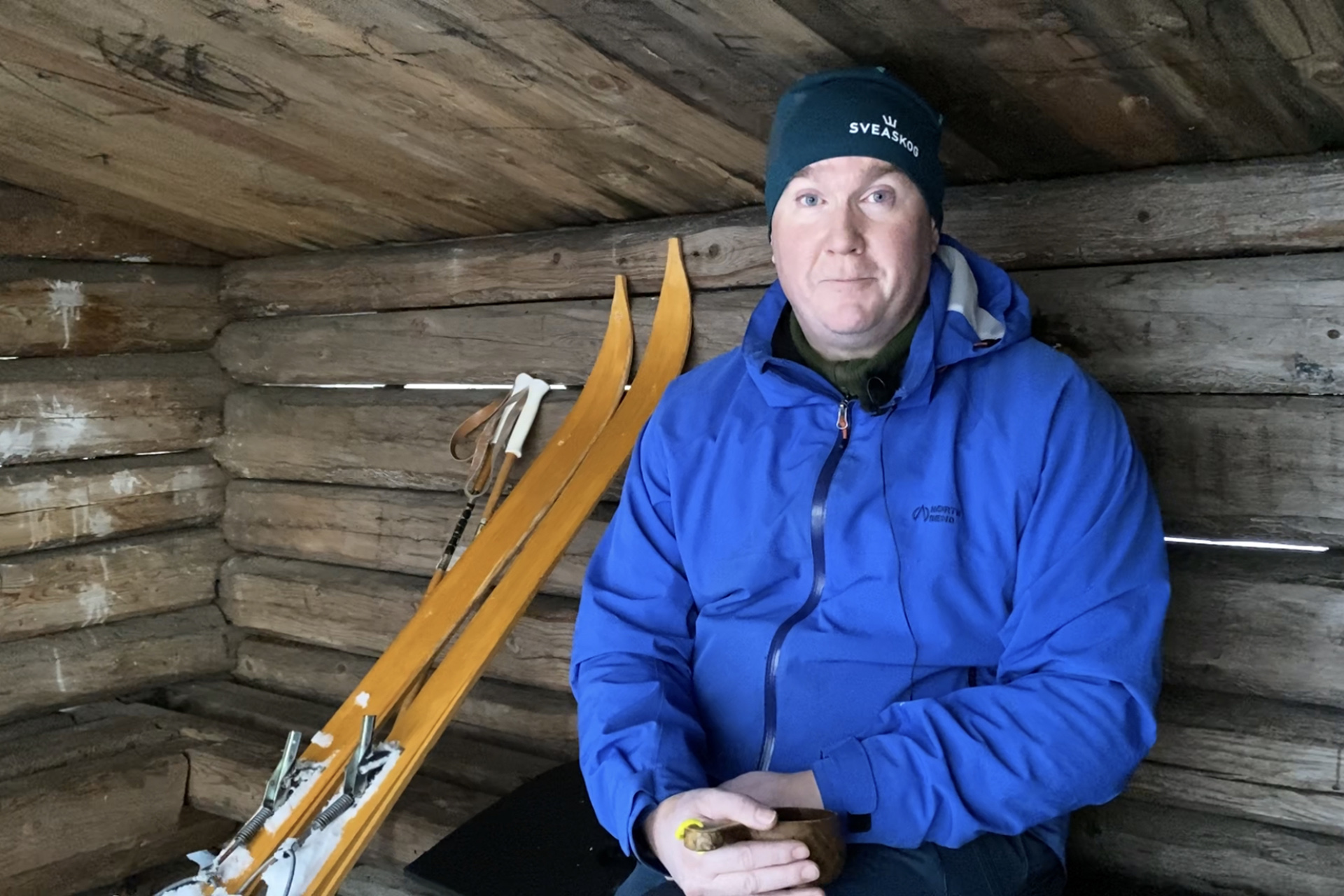 Kyrkoherde Hans Johansson sitter i ett vindskydd och dricker kaffe. Bredvid sig har han ett par turskidor. 
